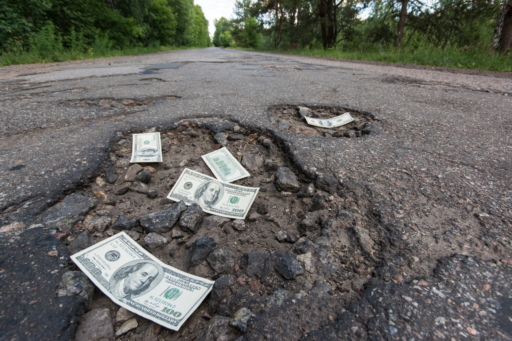 Dollar bills in the potholes on road